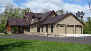 Steel roofing system on a luxury home with tan siding and garage doors